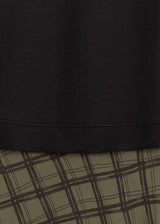 Close-up of a garment showing a solid black hem above a brown and beige plaid pattern.