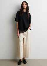 Woman wearing a black oversized shirt and beige pants against a white background