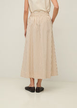 Person wearing a beige and brown striped skirt on a plain background