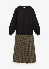 A long-sleeve midi dress with a solid black top half and a brown and olive green plaid skirt half, displayed flat against a light gray background.