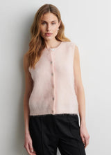 Woman wearing a light pink sleeveless top with buttons against a plain background