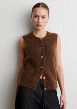 Woman wearing a brown sleeveless knitted vest against a plain background