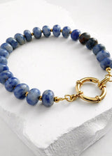 Blue beaded bracelet with a gold clasp on a white surface