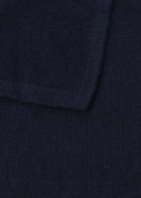 Close-up of a dark navy knit fabric with a folded corner showing the texture and ribbed edge.