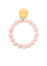 A beaded stretch bracelet featuring light pink round beads and a gold-tone circular disc charm engraved with the brand name 'ANNELE JACOBS'.