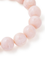 A close-up of a beaded bracelet made of smooth, pale pink round beads on a clean white background.