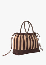 A brown and beige vertically striped canvas drawstring tote bag with dark brown leather handles, shown on a plain light gray background.