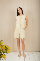 Woman wearing a light-colored sleeveless dress with floral patterns against a beige background